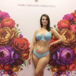 Lingerie model malgos.iak posing in a light blue lace set against a floral background at the Lingerie Salon 2026 trade show in Lodz