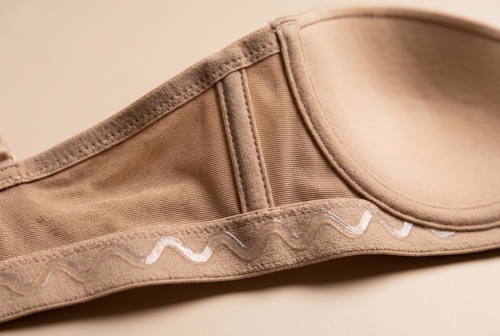 Inside view of a strapless bra band showing flexible vertical side boning and silicone gripper tape